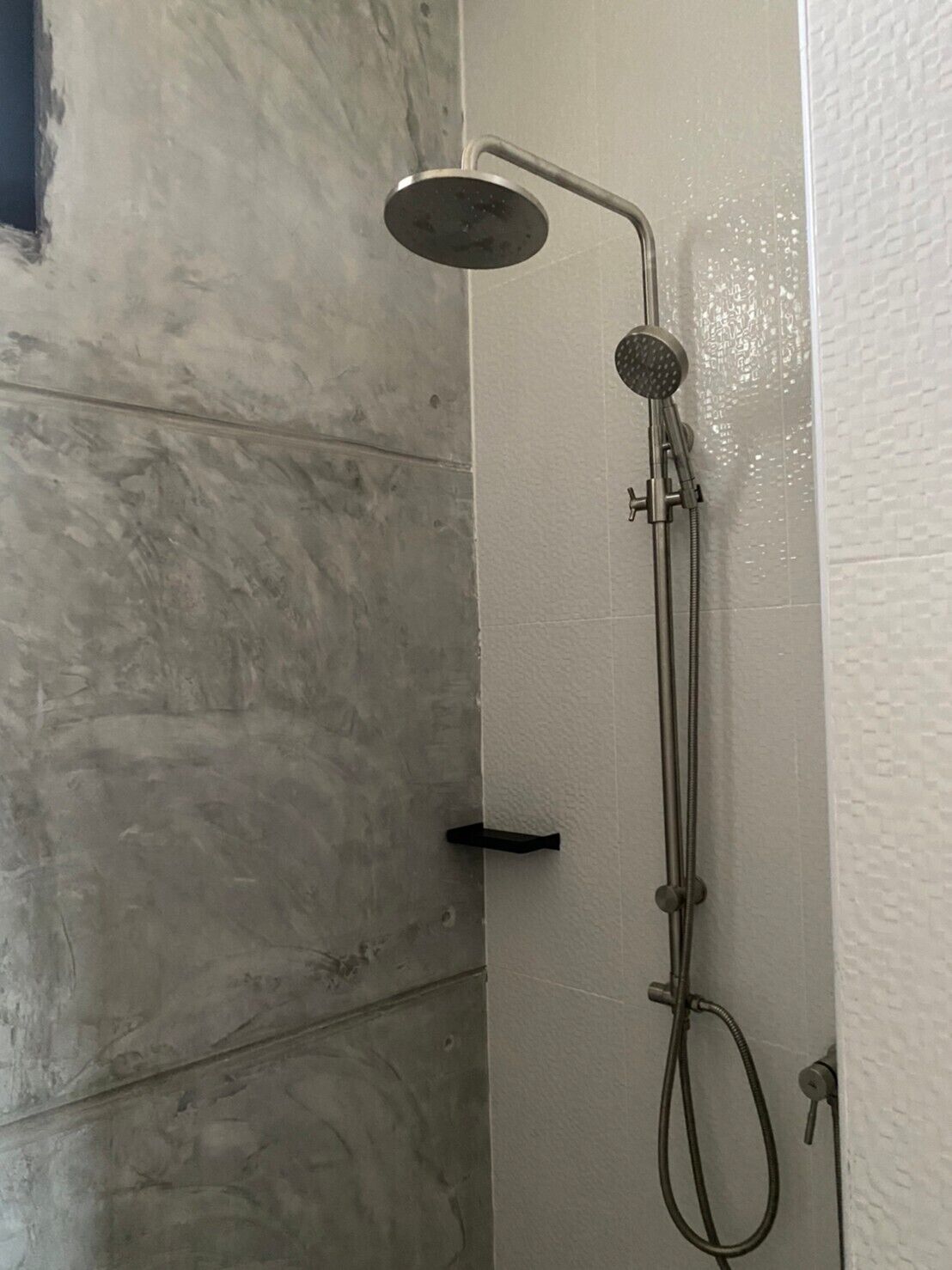 A shower with a handheld showerhead and a handheld hose.