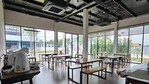 A spacious indoor area with high ceilings, large windows, and multiple tables and chairs. - Destino Hotel Surin (Surin)