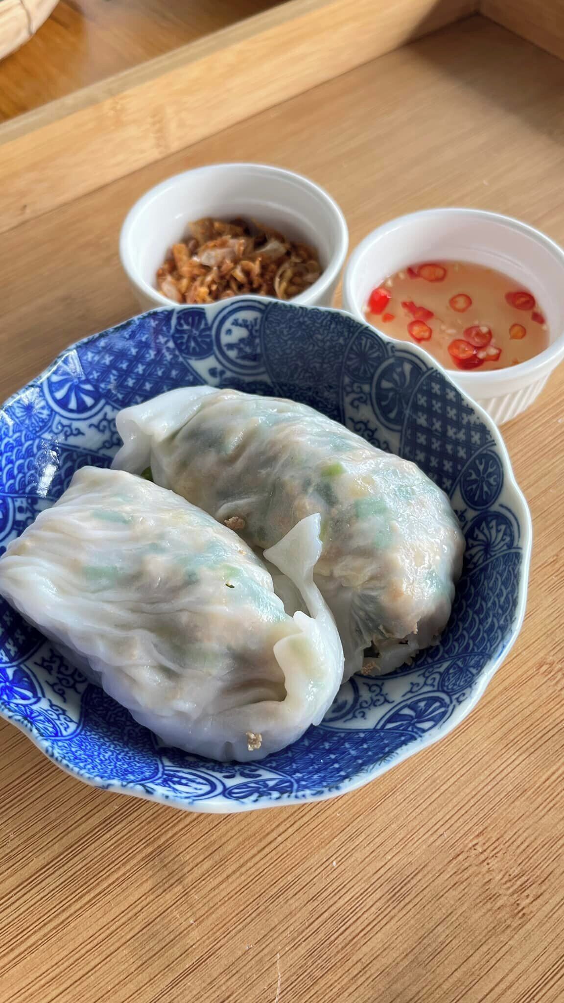 A bowl of fresh spring rolls on a wooden table.