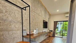 A modern hotel room with a wooden bench, a small refrigerator, a TV mounted on the wall, and a balcony with a view of greenery. - Destino Hotel Surin (Surin)