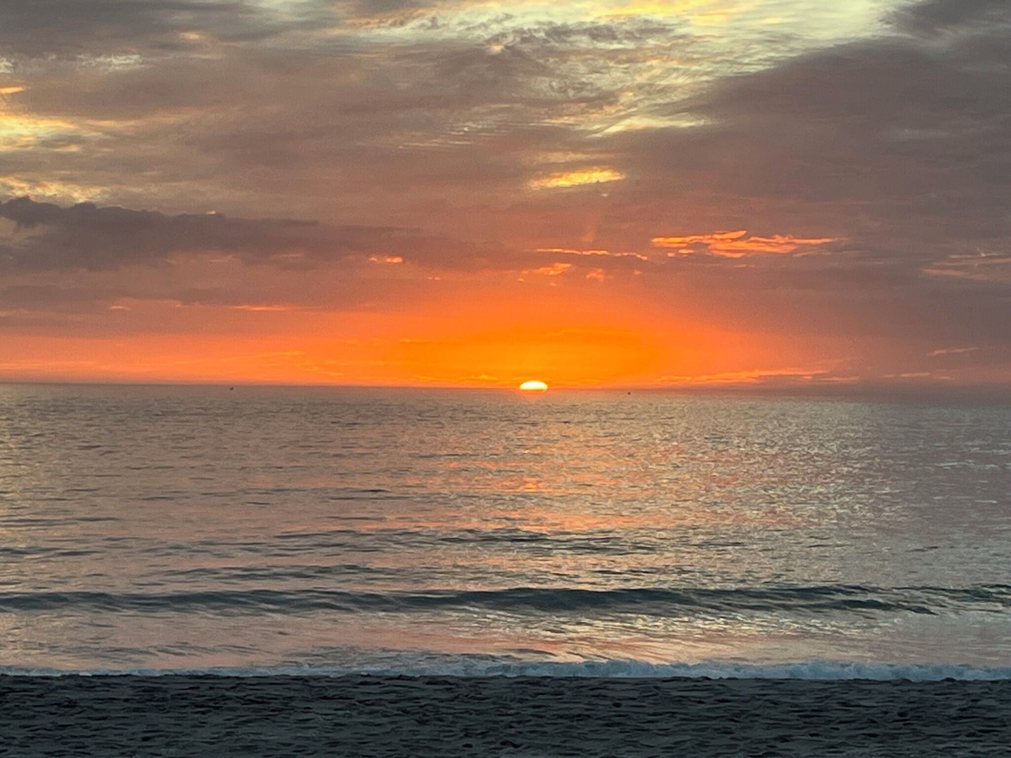 A sunset over the ocean with a clear sky.