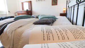 A bed with a book on it, a dresser, a mirror, and a painting on the wall. - Azzurra's House Near the sea in Otranto (Otranto)