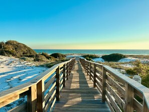 A wooden boardwalk leading to a beach with dunes and a sign indicating it's a sanctuary.