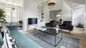 Uma sala de estar moderna com sofá, mesa de centro, cadeiras, televisão e escada.