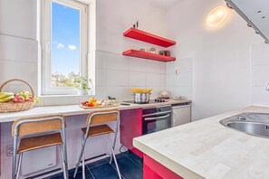 A modern kitchen with a window, a sink, a stove, and two bar stools. - Spacious Apartment In Heart Of Zagreb, Zagreb, Croatia (Zagreb)