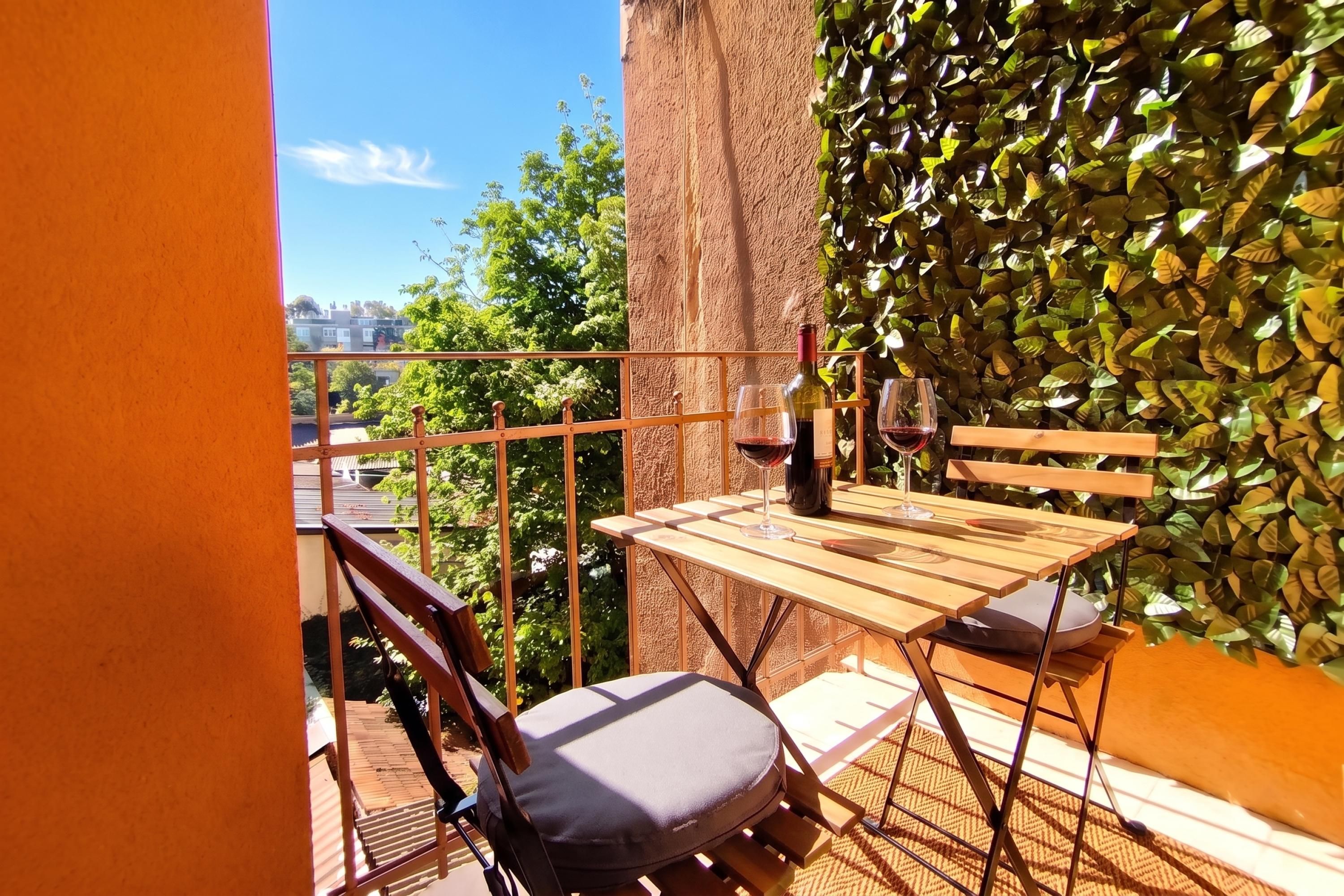Un balcon avec une table, des chaises et une bouteille de vin.