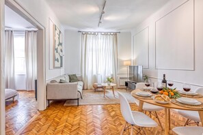Een moderne woonkamer met een bank, een eettafel voor twee personen en een televisie.