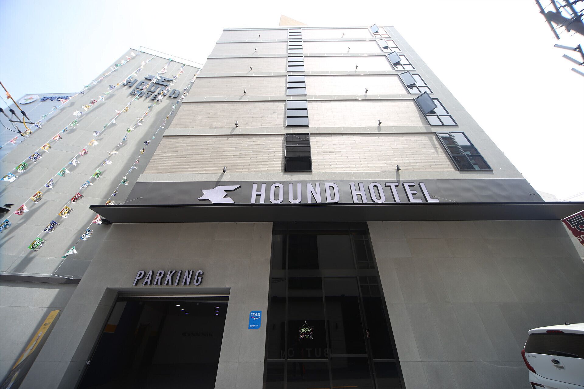 The exterior of the HOUND HOTEL with a visible entrance and a sign indicating a parking area.