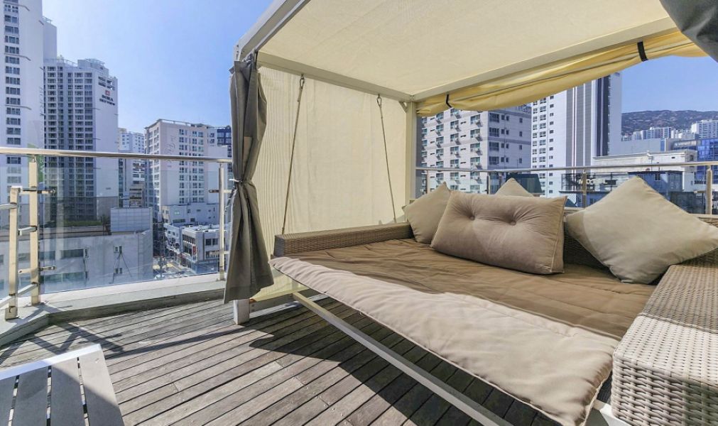Un balcón con una cama, una silla y vistas a la ciudad.
