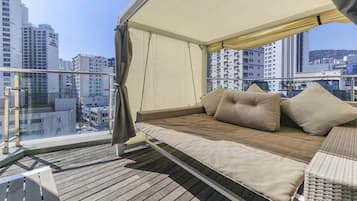 Un balcón con una cama, una silla y vistas a la ciudad.