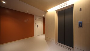 A modern elevator with a digital display, a door with a number plate, and a corridor with a floor number sign. - Hound Hotel Sajik Minam Station (Busan)