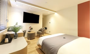 A modern hotel room with a bed, a desk, a chair, a TV, and a potted plant. - Hound Hotel Sajik Minam Station (Busan)