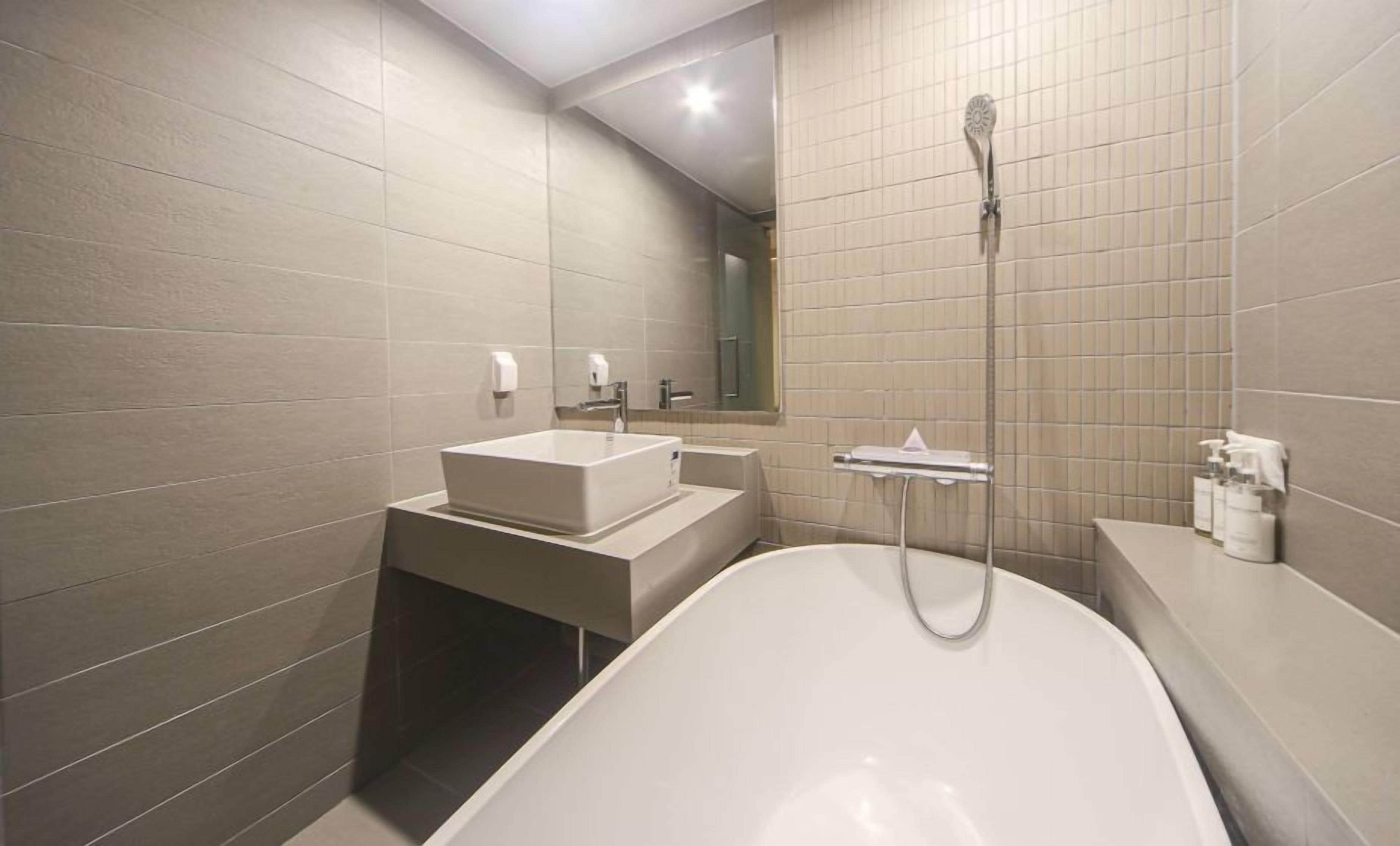 Un baño moderno con una bañera independiente, un lavabo y un cabezal de ducha.