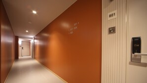 A hotel corridor with a brown wall, a white door with the number 801, and a HIONE elevator control panel. - Hound Hotel Sajik Minam Station (Busan)
