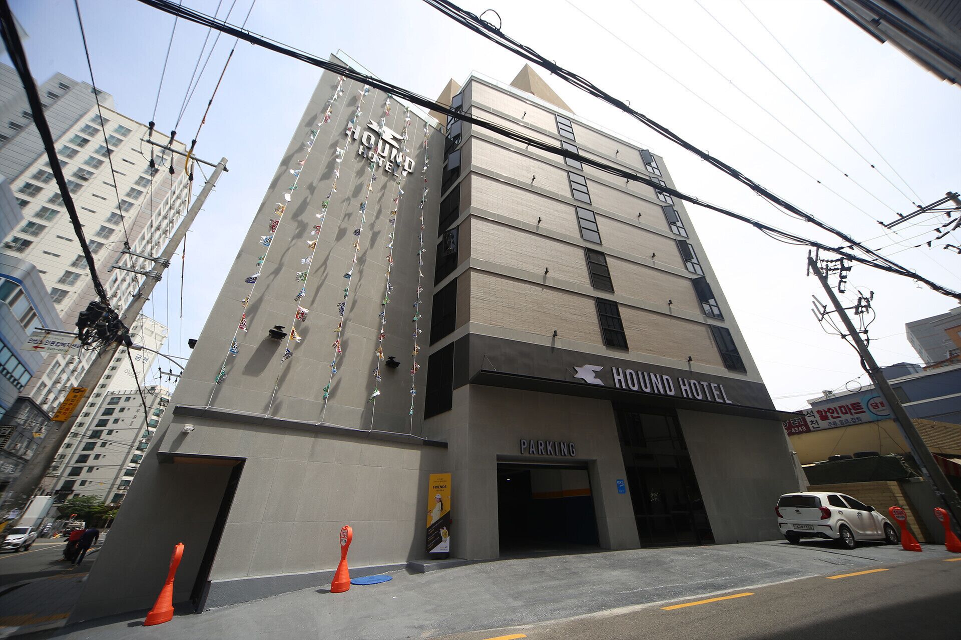 Un edificio de varios pisos con un letrero que dice "HOUND HOTEL" y una entrada para "ESTACIONAMIENTO".