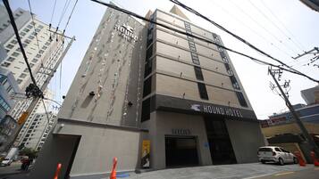 Un edificio de varios pisos con un letrero que dice "HOUND HOTEL" y una entrada para "ESTACIONAMIENTO".