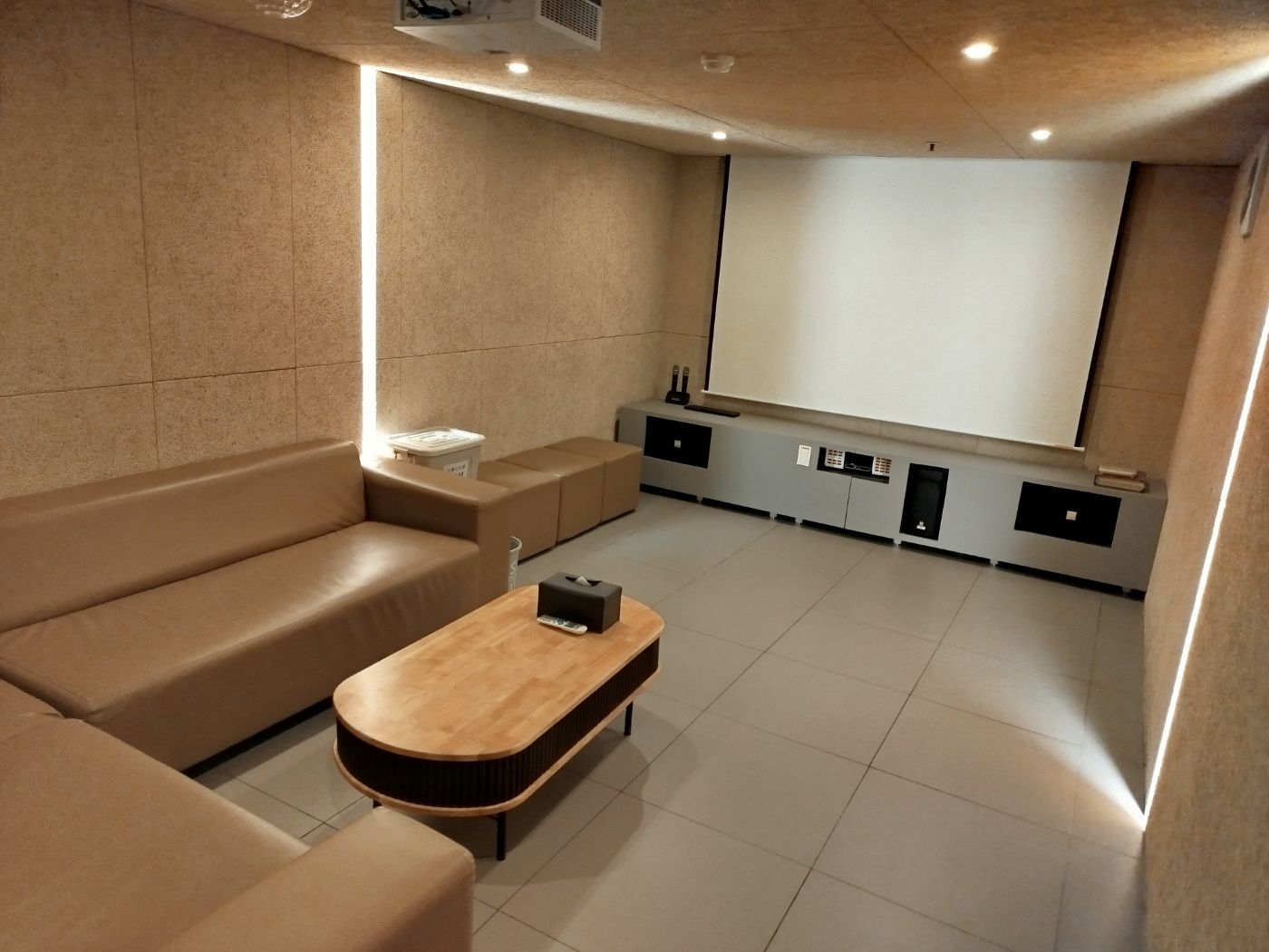 A modern living room with a large flat-screen TV, a wooden coffee table, and a sofa.