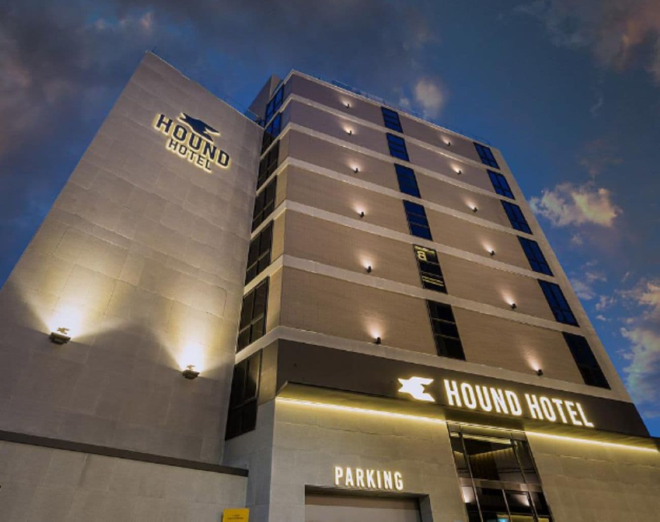 A Hound Hotel building with a modern design, featuring multiple floors and a prominent sign.
