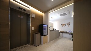 A hotel reception area with a reception desk, a glass display case, and an elevator. - Hound Hotel Sajik Minam Station (Busan)
