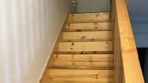 Eine Holztreppe mit Geländer, die zu einer Zwischenebene mit einer Tür führt.
