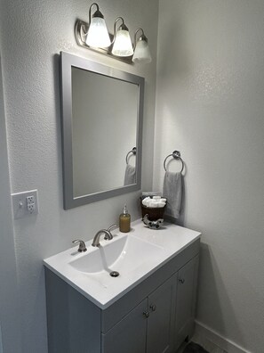A bathroom with a white sink, a mirror, and a towel rack.