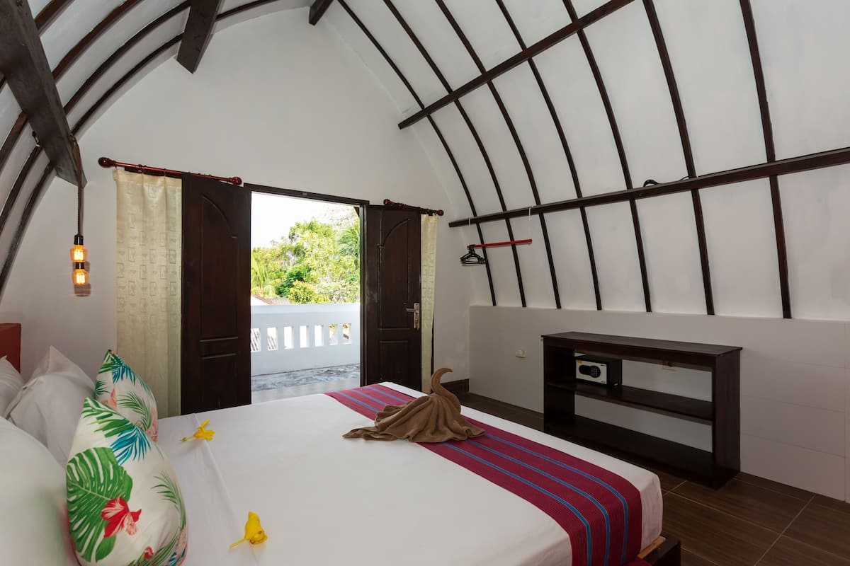 Un dormitorio con cama, mesita de noche, armario y vistas a zonas verdes.