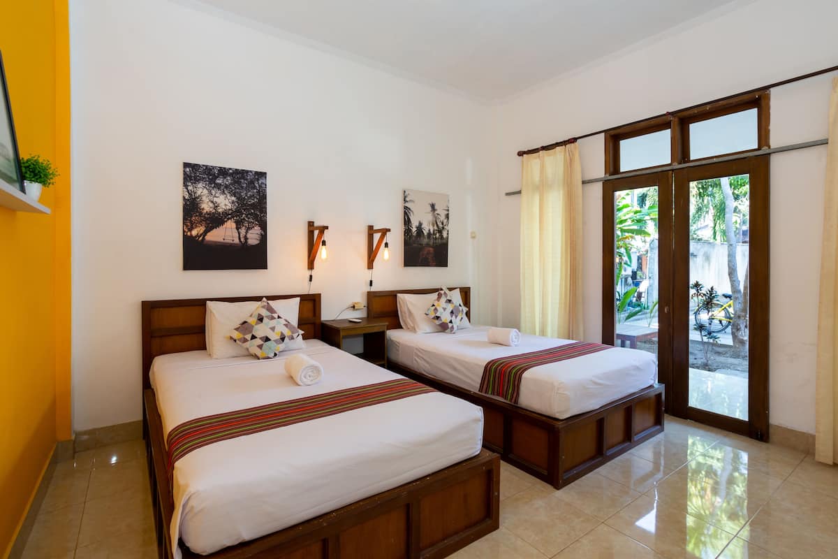 Habitación de hotel con dos camas, una mesita de noche, una ventana con cortinas y una obra de arte en la pared.