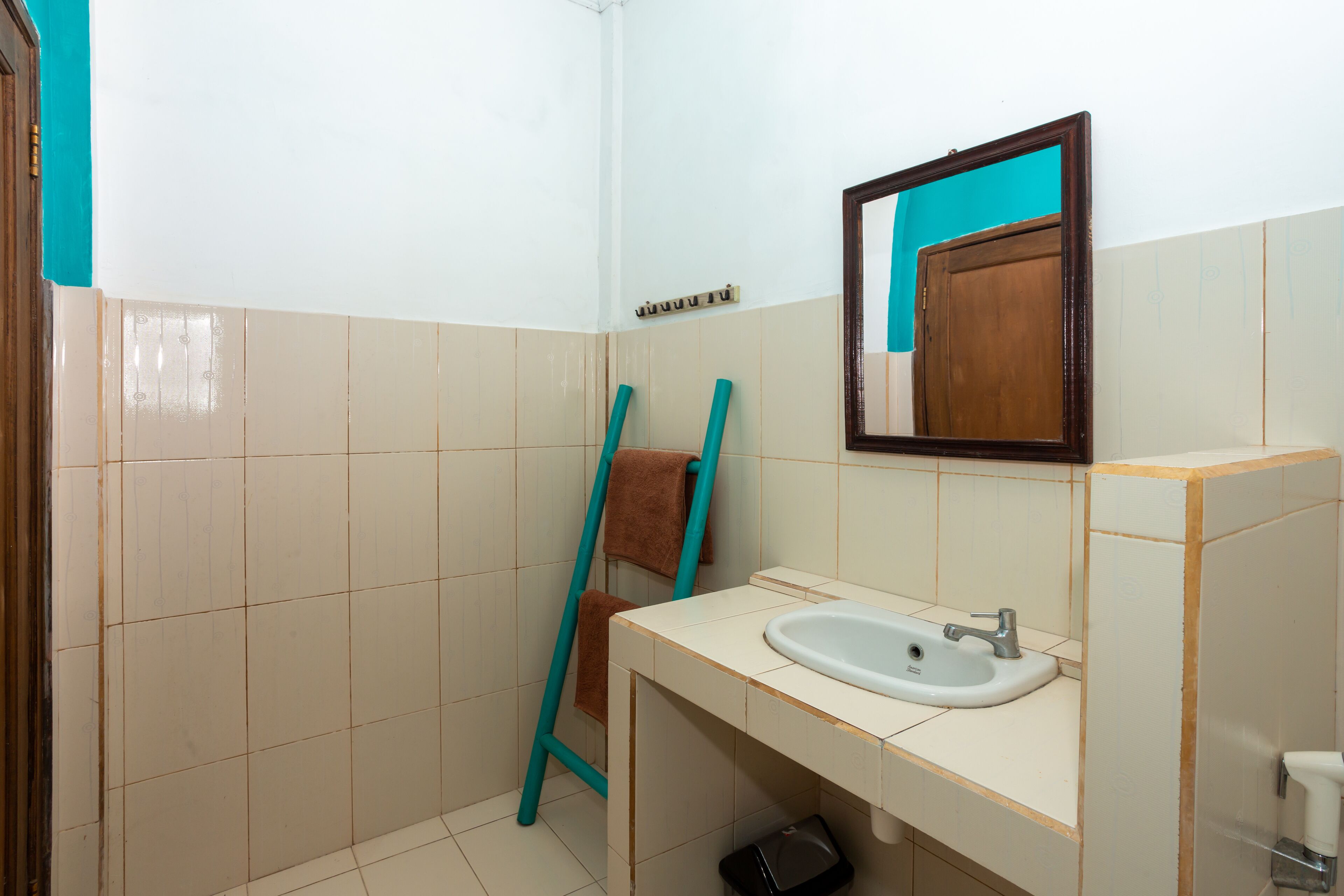 A bathroom with a white sink, a mirror, and a towel rack.