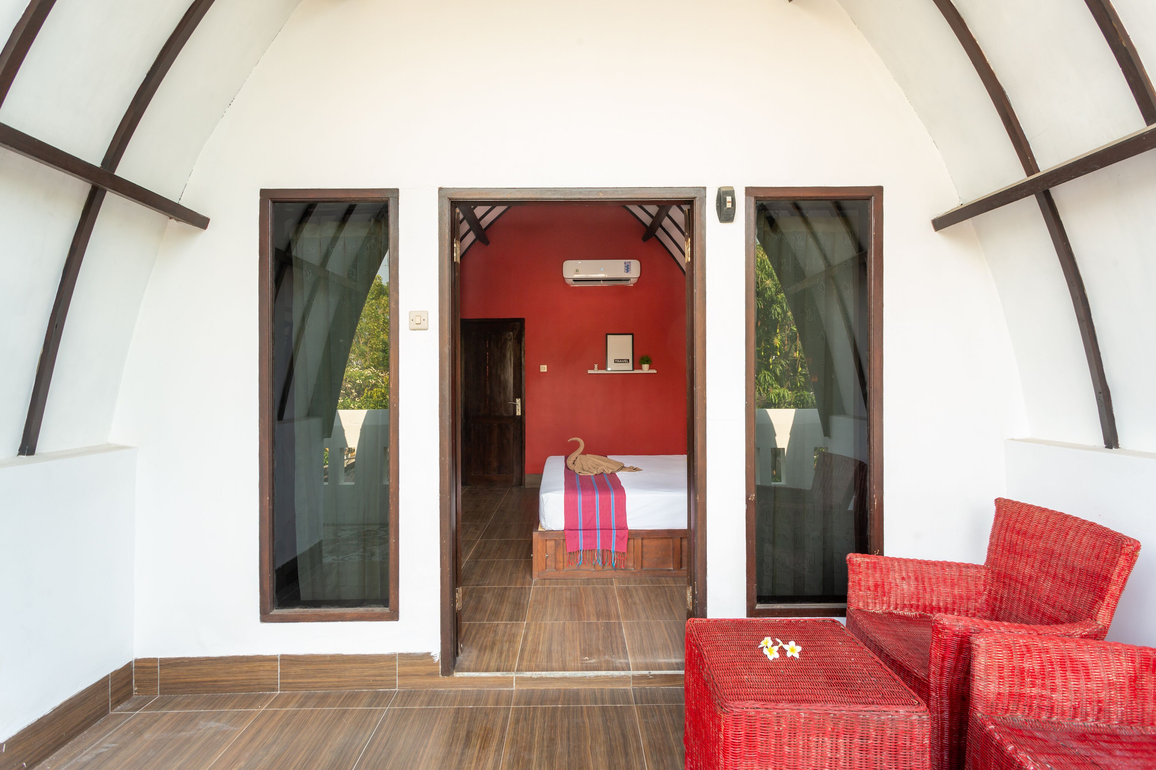 A room with a bed, a red chair, and a small table.