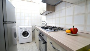A modern kitchen with a washing machine, a stove, and a sink. - Luce Holiday Home With air Conditioning for 5 Guests (Melendugno)
