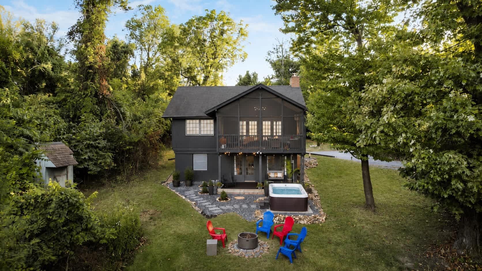 A two-story house with a deck, a hot tub, and outdoor seating.