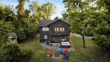 A two-story house with a deck, a hot tub, and outdoor seating.