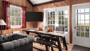 Una habitación acogedora con detalles de madera, una mesa de comedor con sillas, un sofá y un televisor de pantalla plana montado en la pared.