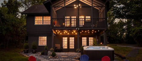 A two-story house with a balcony, outdoor seating, and a hot tub.