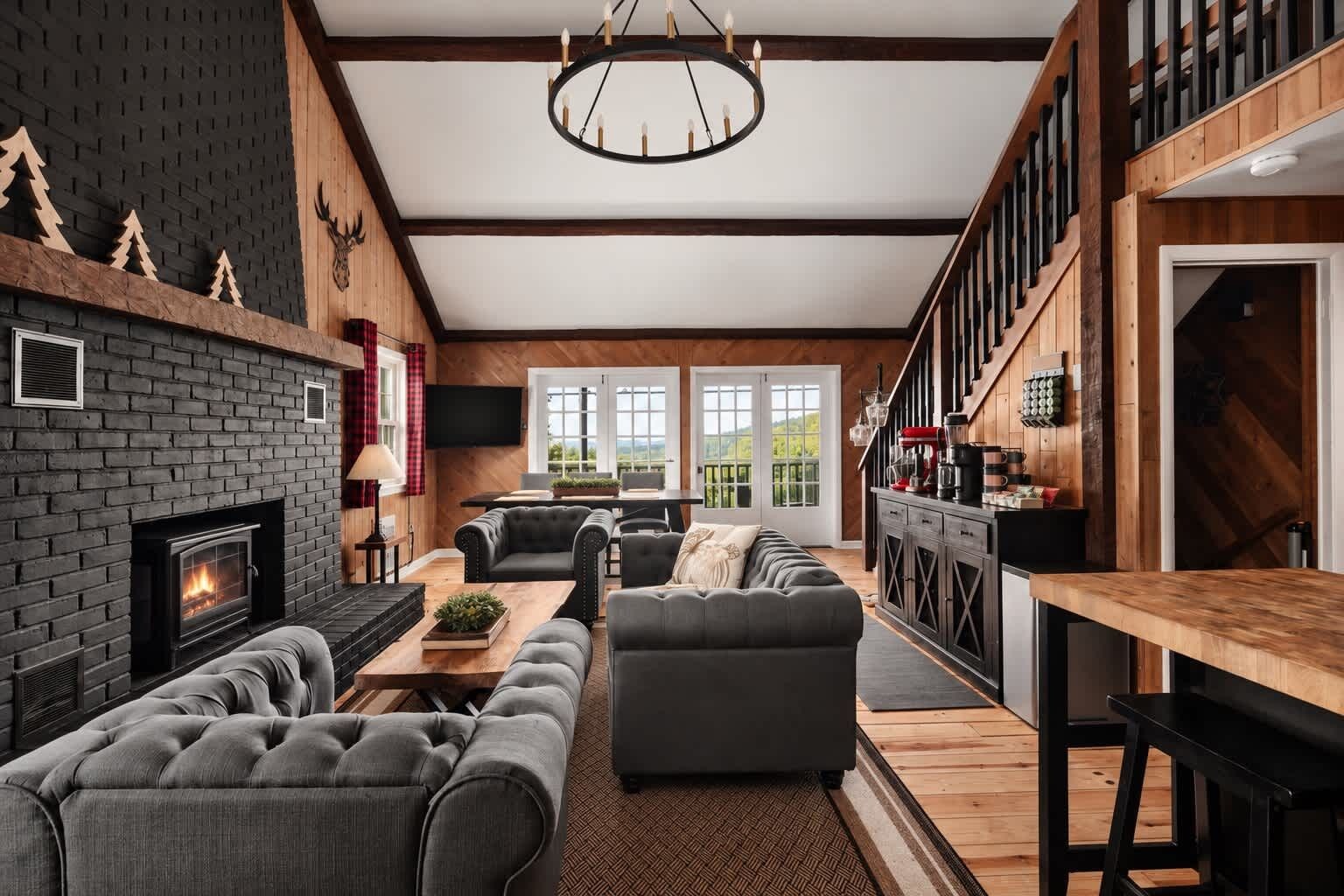 Ein modernes Wohnzimmer mit Kamin, Sofas, einer Essecke und einer Küche mit Holzelementen.
