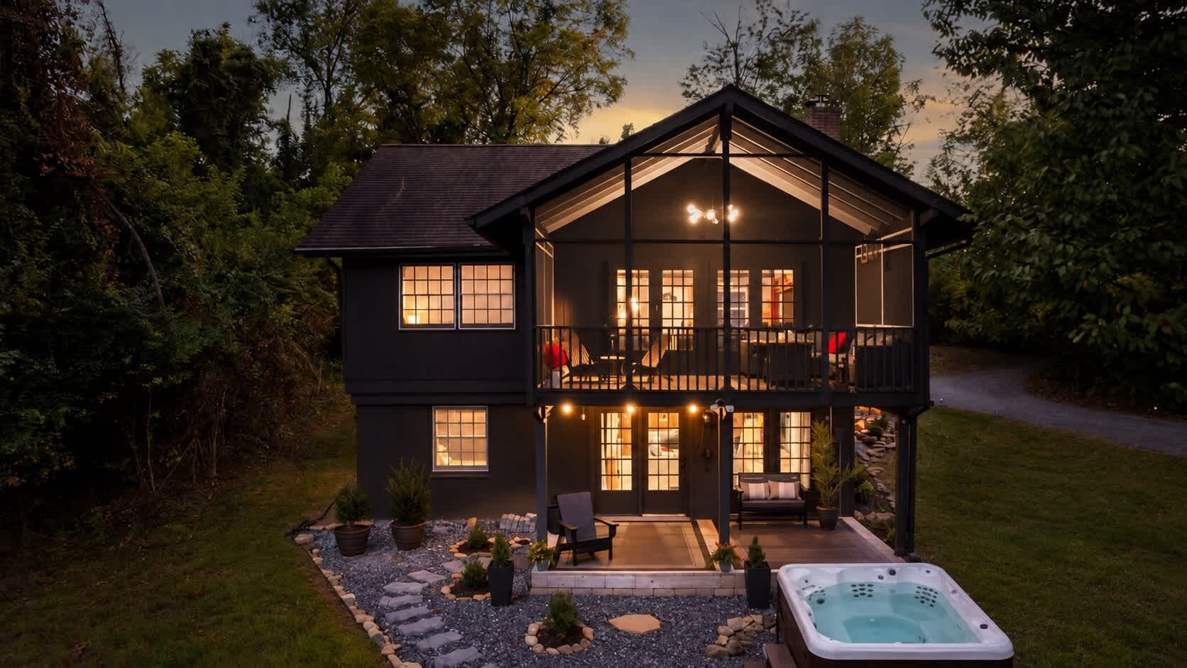 A two-story house with a balcony, a hot tub, and a stone pathway leading to the entrance.