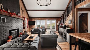Una sala de estar moderna con chimenea, un sofá, un comedor y una cocina con encimera de madera.