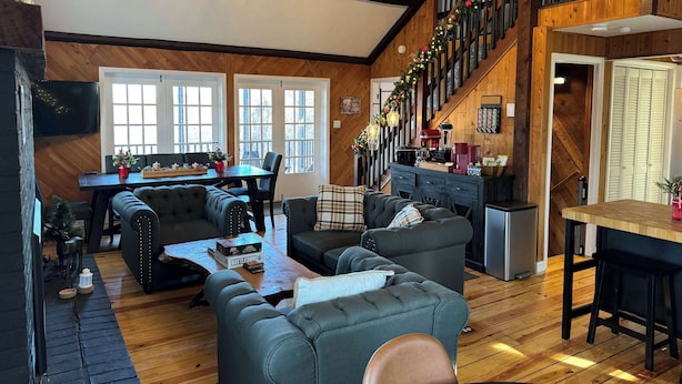 A cozy living room with a fireplace, a dining area, and a staircase. - Far View Shenandoah | Hot Tub, Movie & Game Room, Valley Views | 3BR & Sleeps 6 (Front Royal)