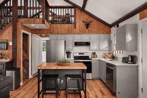 Una cocina moderna con una isla de madera, armarios grises y una cabeza de venado montada.
