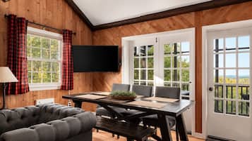 Une pièce avec un intérieur en bois, un téléviseur à écran plat fixé au mur, une table à manger avec des chaises et un canapé.