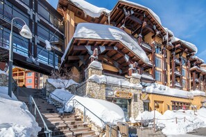 A multi-story hotel with a stone facade, wooden balconies, and a staircase leading to the entrance. - Steps to Gondola – Upgraded 2BR, 2.5BA Condo 577 (Mammoth Lakes)