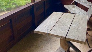 A wooden deck with a table and chairs, overlooking a forested area with trees and a distant view of a mountain range. - Fisherman's Cove (Mena)