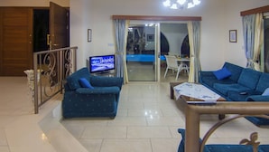 A living room with a sofa, a coffee table, a TV, and a dining area with a table and chairs. - Amazing Pool, Complete Privacy, Amenities and Beach Nearby (Pegeia)