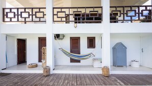 A two-story building with a wooden deck, a hammock, and a pool.
