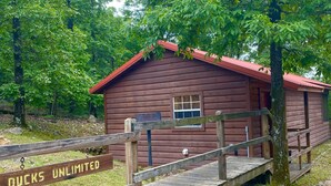 Eine rustikale Holzhütte mit rotem Dach, umgeben von üppigem Grün.