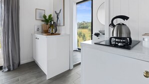 Une cuisine moderne avec une bouilloire, une bouteille de vin et une plante sur le plan de travail.