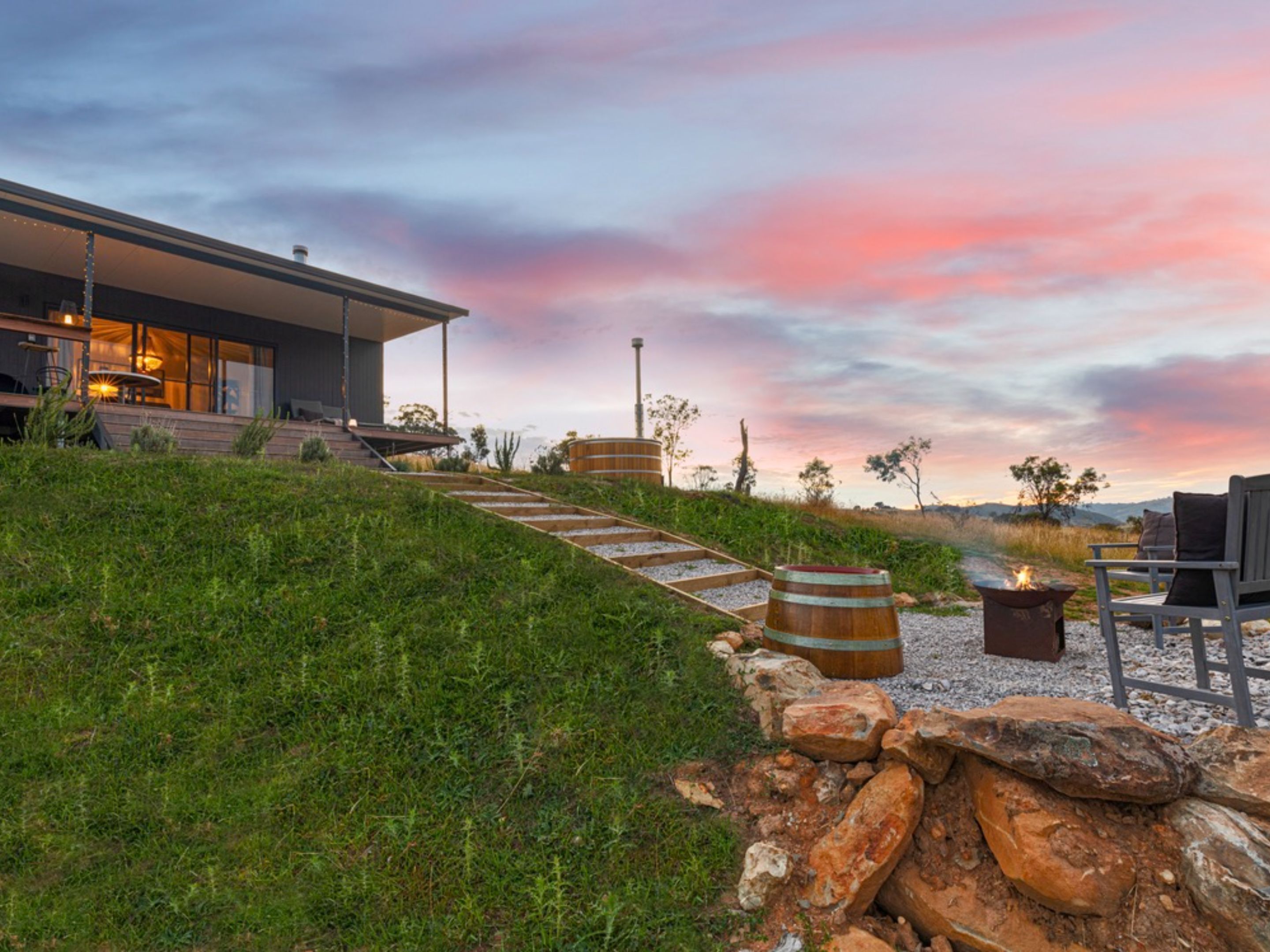 A modern house with a patio area, a fire pit, and a view of the landscape.