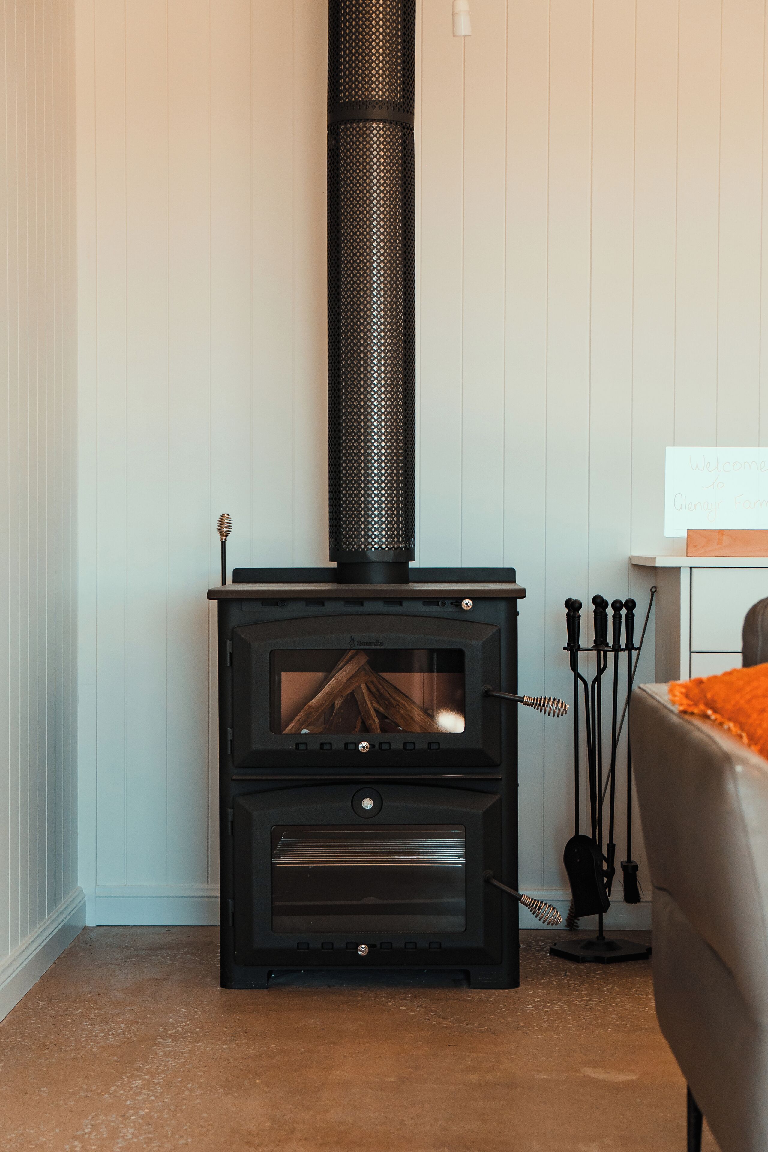 A wood-burning stove with a chimney, a sign, and a chair.