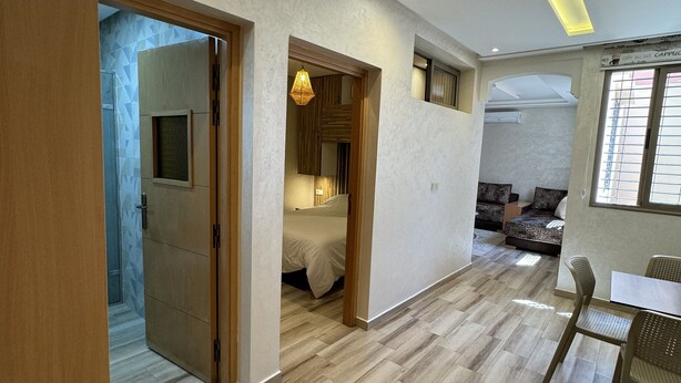 Ein moderner Wohnraum mit Holzboden, einer Essecke mit Tisch und Stühlen sowie einem Schlafzimmer mit Bett und Pendelleuchte.