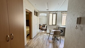 Ein geräumiges Zimmer mit einem Holzschrank, einer Essecke mit Tisch und Stühlen sowie einer Waschküche mit Waschmaschine.